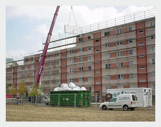 Wohnblock mit Kran und Containern während der Entkernung